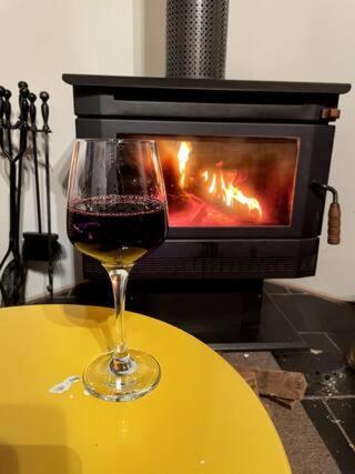 um copo de vinho sentado numa mesa em frente a uma lareira em Tranquil Holiday house in Kevington em Kevington