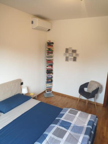 - une chambre avec un lit, une chaise et une étagère dans l'établissement Confortevole bilocale a Basiglio - Milano 3, à Basiglio