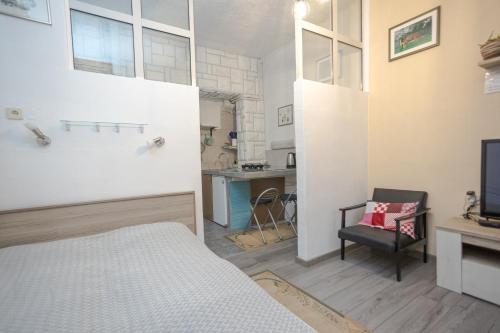 1 dormitorio con cama, escritorio y cocina en Studio apartman Kamenčić, en Osijek