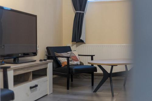 a living room with a tv and a chair and a table at Studio apartman Kamenčić in Osijek