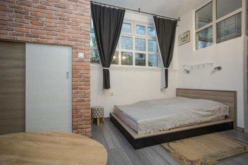 a bedroom with a bed and a brick wall at Studio apartman Kamenčić in Osijek