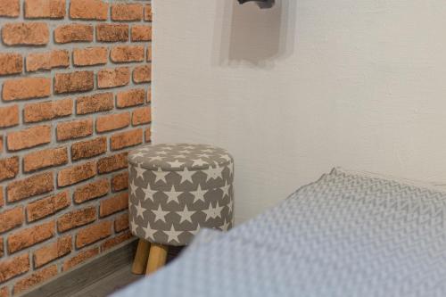 a bedroom with a brick wall and a stool at Studio apartman Kamenčić in Osijek