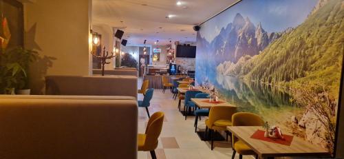 a restaurant with tables and chairs and a large painting on the wall at Willa Ostoja u Pyrca in Zakopane