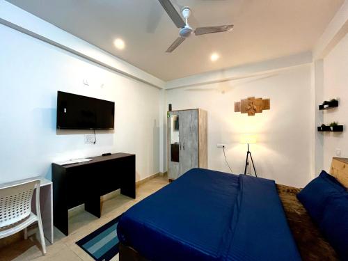 um quarto com uma cama azul e uma televisão de ecrã plano em Adinova em Kasol