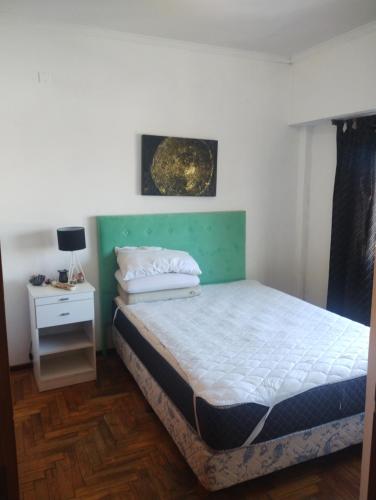 Schlafzimmer mit einem Bett mit einem grünen Kopfteil in der Unterkunft Departamento frente al mar in Mar del Plata