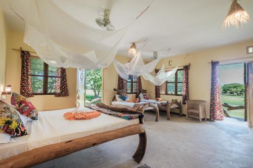 a room with a bed and a table and windows at Lake Natron Maasai giraffe eco Lodge and camping in Mtowabaga