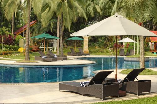 a pool with lounge chairs and an umbrella at Aryaduta Pekanbaru in Pekanbaru