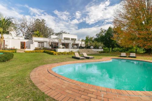 a swimming pool in the yard of a house at Edenbrook Country Manor in Plettenberg Bay
