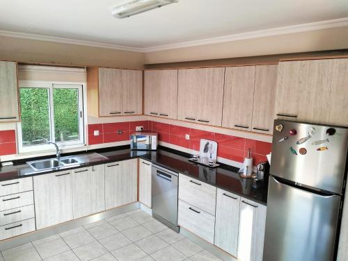 Una cocina con gabinetes de madera y un refrigerador de acero inoxidable. en VILLA ANDORINHA with Private Pool in a quiet area, en Aljezur