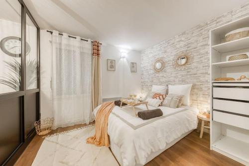 a bedroom with a white bed and a brick wall at La Verrière - 2mn centre ville in Corbeil-Essonnes