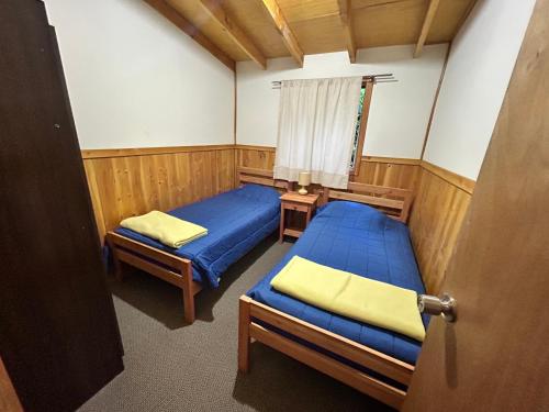 a small room with two beds and a window at Cabañas El Boldo in Licán Ray