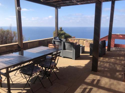 um pátio com uma mesa e cadeiras e o oceano em Villa su Capo Bianco em Ponza