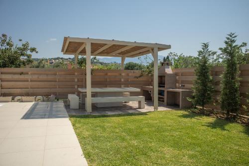 a picnic table in a backyard with a wooden fence at Luxury Villa Chrisi in Svoronata