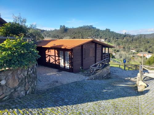 a small wooden cabin with a stone wall at Vilas da Matagosa in Matagosinha