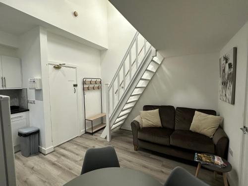 a living room with a couch and a staircase at Central Colwyn Bay F1 in Colwyn Bay