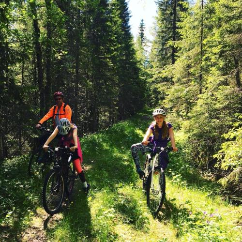 two people riding bikes on a trail in the woods at Landlig leilighet in Landsem