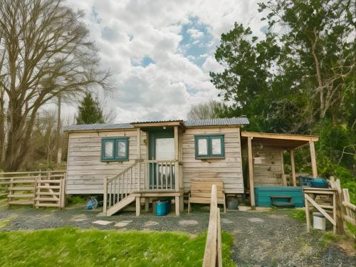 um chalé de madeira com um alpendre e uma cerca em Lle Mary - Beautiful views, Hot tub, Secluded, Dog Welcome, Barmouth em Llanddwywe