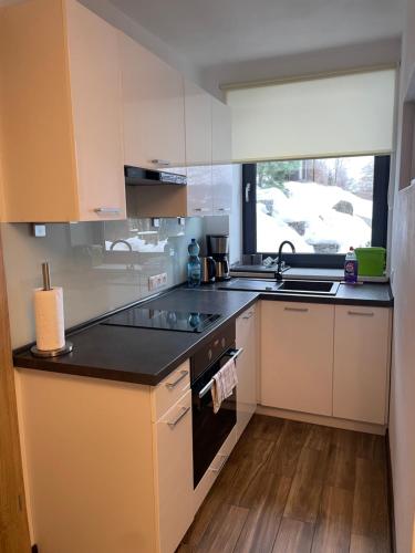 a kitchen with white cabinets and a black counter top at Apartamenty Carpe Diem in Ustroń