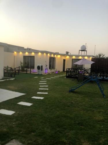 um edifício com um relvado com mesas e uma tenda em شالية أوجن em Unayzah