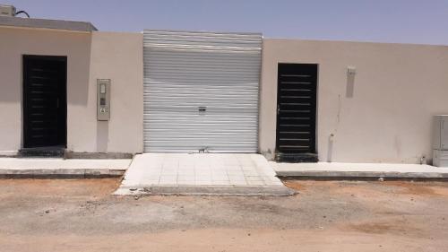 uma grande porta de garagem metálica num edifício branco em شالية أوجن em Unayzah