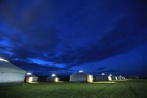 uma fila de tendas brancas num campo à noite em maidar-san tourist camp 