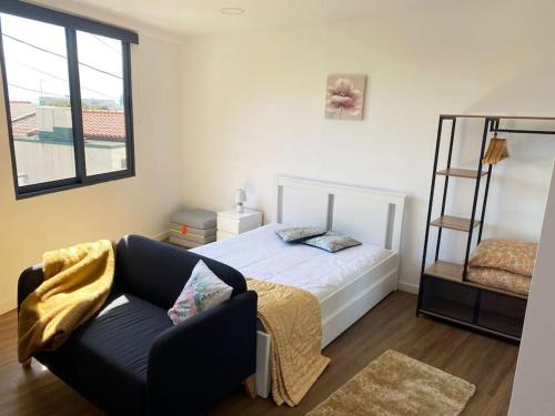 a bedroom with a bed and a chair and a window at Machico center w/ terrace 5 min beach in Machico