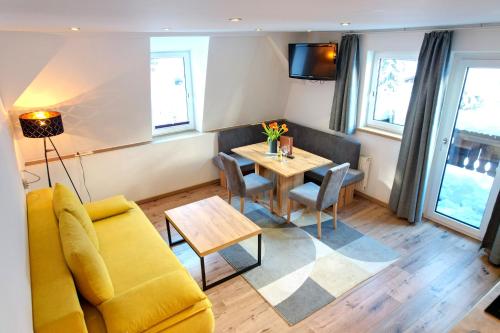 a living room with a yellow couch and a table at GRUBERS, Hotel Appartments Gastein in Bad Gastein