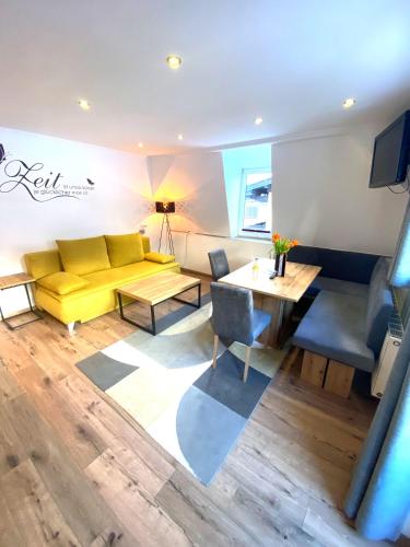 a living room with a yellow couch and a table at GRUBERS, Hotel Appartments Gastein in Bad Gastein