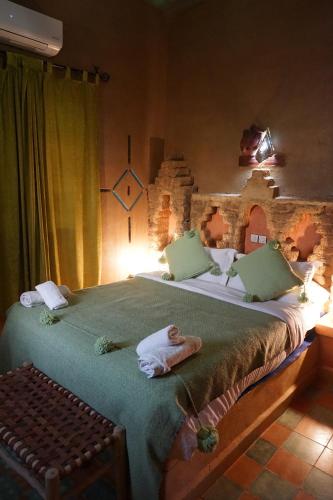 a bedroom with a large bed with green sheets at Riad Dar Poublanc in Merzouga