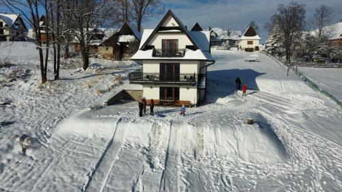 un grupo de personas de pie en la nieve frente a una casa en Leszczyniański Domek en Biały Dunajec