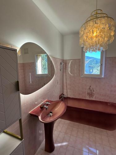 a bathroom with a sink and a tub and a chandelier at Seaview Garden Villa in LʼÎle-Rousse