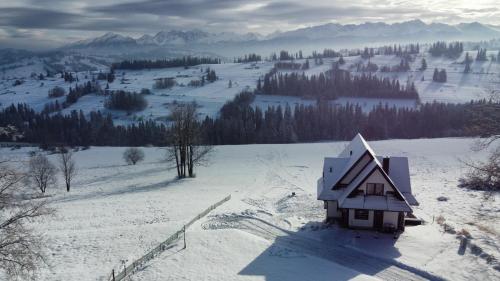 a small house sitting on top of a snow covered hill at Leszczyniański Domek in Biały Dunajec