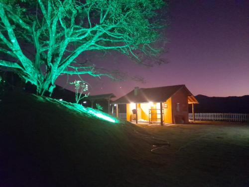 a house lit up at night with green lights at Chalé Mirante Da Guapiara in Aiuruoca