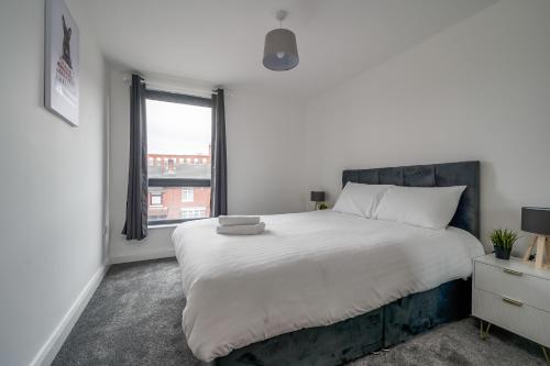 ein Schlafzimmer mit einem großen weißen Bett und einem Fenster in der Unterkunft BOYEILLES BELFAST 2 BED MODERN COZY APARTMENT in Belfast