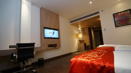 a hotel room with a bed and a flat screen tv at Ramada by Wyndham Aligarh GT Road in Alīgarh