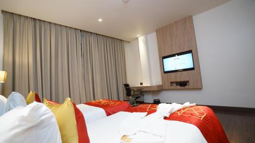 a hotel room with two beds and a flat screen tv at Ramada by Wyndham Aligarh GT Road in Alīgarh