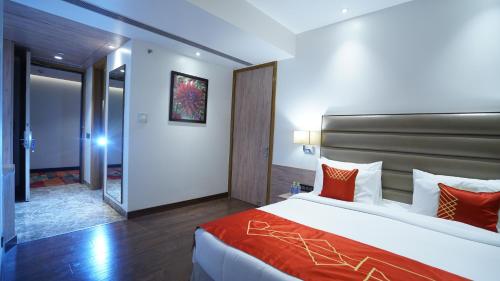 a bedroom with a large bed with red pillows at Ramada by Wyndham Aligarh GT Road in Alīgarh