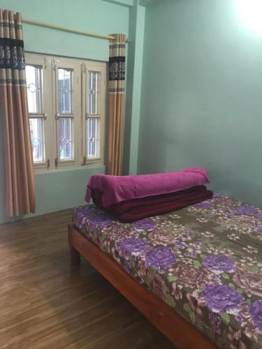 a bedroom with a bed with purple sheets and windows at Little Heaven Restaurant & Guesthouse in Deorāli