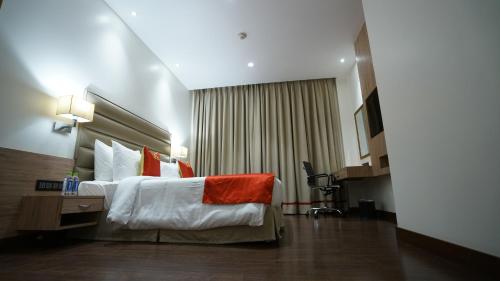a hotel room with a bed and a desk at Ramada by Wyndham Aligarh GT Road in Alīgarh