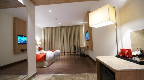 a hotel room with a bed and a television at Ramada by Wyndham Aligarh GT Road in Alīgarh