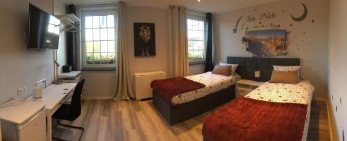 a bedroom with two beds and a desk and windows at Dormitorium Kaarst Wohnraum auf Zeit in Kaarst