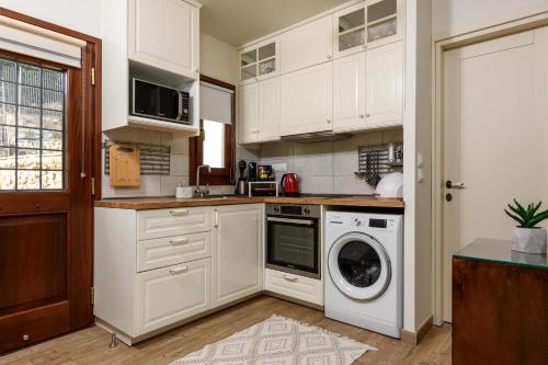 a kitchen with white cabinets and a washer and dryer at Enavlion Luxury Domes in Panayia