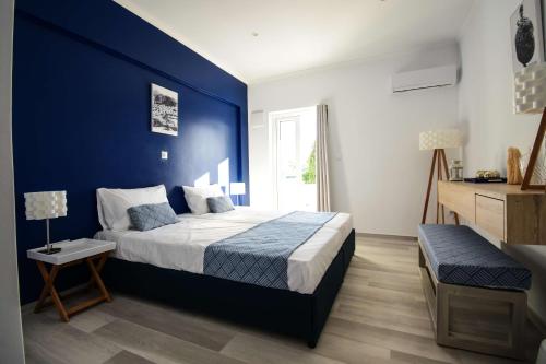 een blauwe slaapkamer met een bed en een blauwe muur bij Aphrodite Studios Kalymnos in Myrties