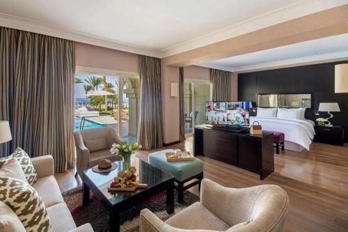 a hotel room with a bed and a living room at Rixos Sharm El Sheikh - Adults Only 18 Plus in Sharm El Sheikh
