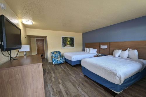 a hotel room with two beds and a flat screen tv at Days Inn by Wyndham Gainesville University in Gainesville