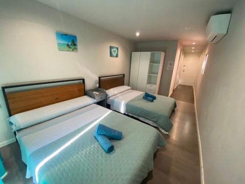 two beds in a bedroom with blue towels on them at Camp Nou Nueva Casa in El Arrabal
