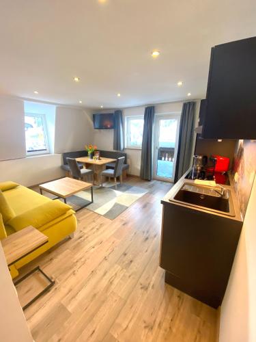 a living room with a yellow couch and a kitchen at GRUBERS, Hotel Appartments Gastein in Bad Gastein