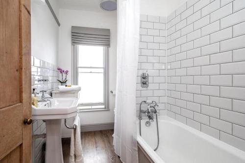 a white bathroom with a sink and a bath tub at Perfect Cosy Cottage in Litcham