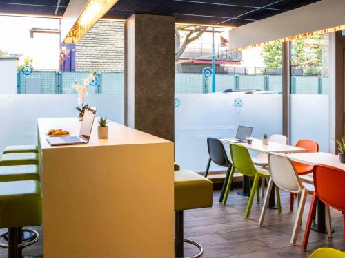 a restaurant with tables and chairs with a laptop on a counter at ibis budget Paris Clichy Mairie in Clichy