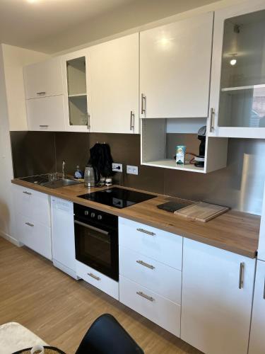 une cuisine avec des armoires blanches et un four à plaques de cuisson dans l'établissement Appt spacieux et calme prox Disney-CDG-Stade de France, au Blanc-Mesnil